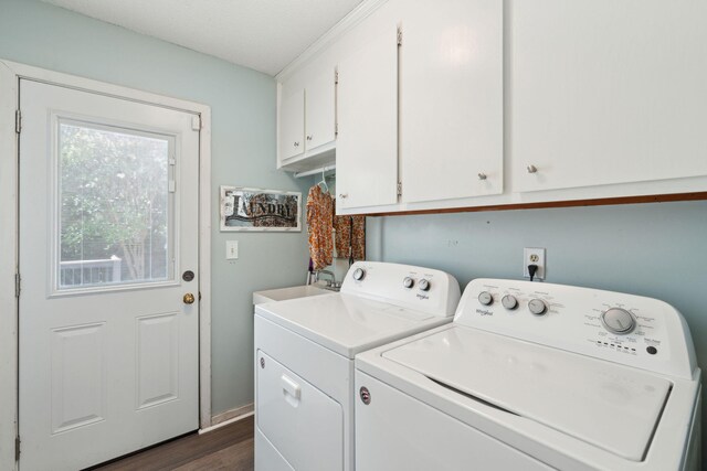 clothes washing area featuring washing machine and clothes dryer, cabinet space, and dark wood-style floors
