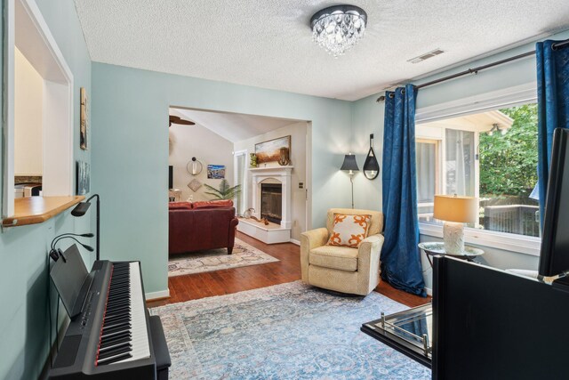 bedroom featuring wood finished floors, a glass covered fireplace, and a textured ceiling