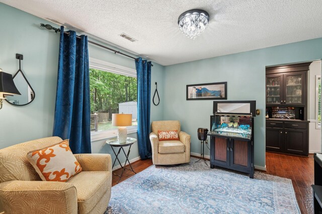 living area featuring wood finished floors, a textured ceiling, and baseboards