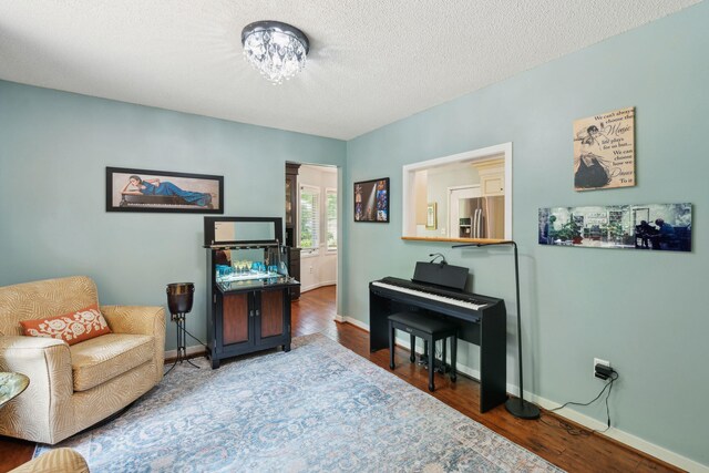 sitting room with wood finished floors, baseboards, and a textured ceiling