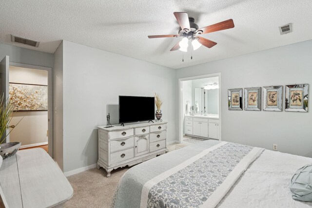 bedroom featuring light carpet, ceiling fan, a textured ceiling, connected bathroom, and baseboards