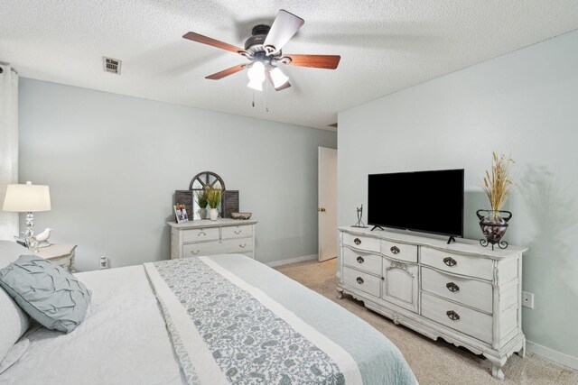 bedroom with light colored carpet, a ceiling fan, baseboards, and a textured ceiling