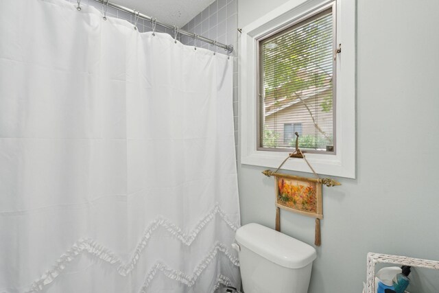bathroom featuring toilet and a shower with curtain