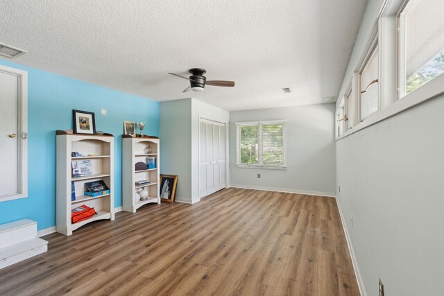 unfurnished living room featuring wood finished floors, ceiling fan, a textured ceiling, and baseboards