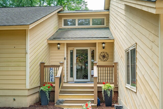 view of exterior entry with a shingled roof
