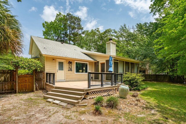 rear view of property with a chimney, a deck, and a shingled roof