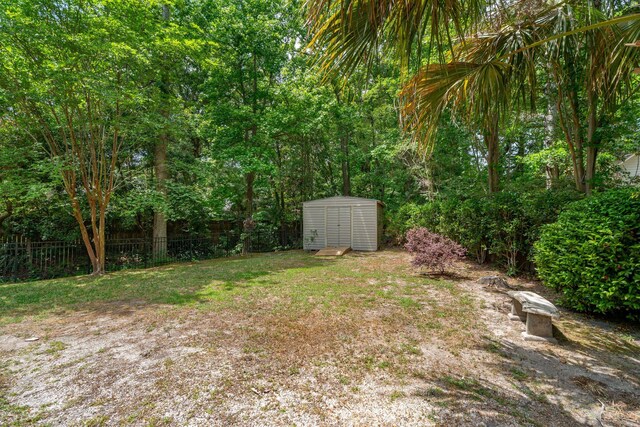 view of yard featuring fence, a storage unit, and an outbuilding