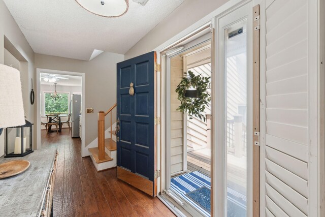 entrance foyer featuring dark wood-style flooring, stairs, a ceiling fan, and a textured ceiling