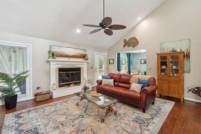 living area with ceiling fan, high vaulted ceiling, wood finished floors, baseboards, and a high end fireplace