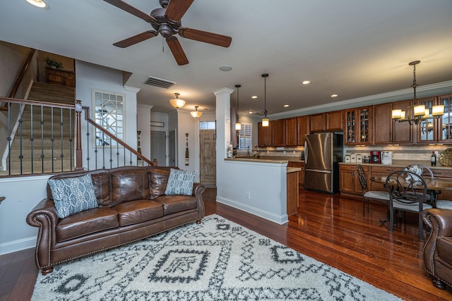 living room featuring ceiling fan with notable chandelier, dark hardwood / wood-style flooring, and crown molding