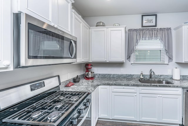 kitchen with light stone counters, white cabinetry, sink, and appliances with stainless steel finishes