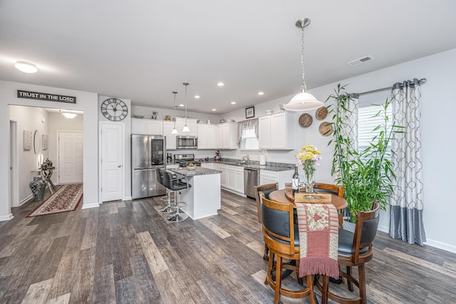 kitchen featuring a breakfast bar, white cabinets, hanging light fixtures, a kitchen island, and stainless steel appliances