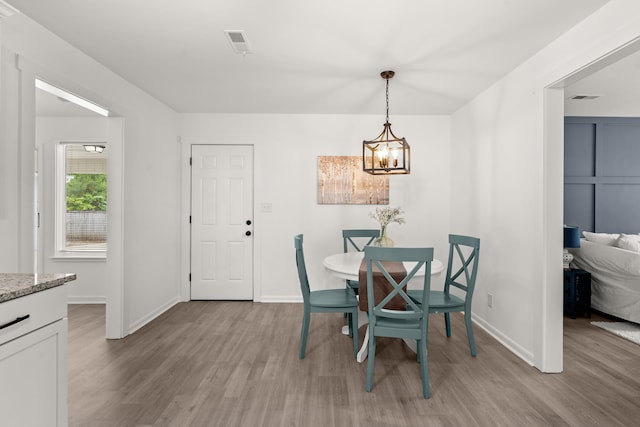 dining room with a chandelier, light wood-style flooring, and baseboards