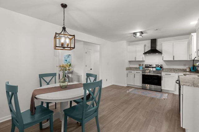 dining area with light wood-type flooring, a chandelier, and baseboards