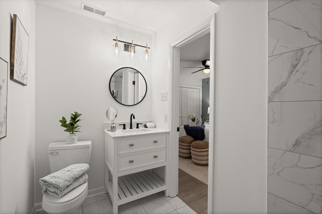 bathroom featuring marble finish floors, toilet, a ceiling fan, vanity, and ensuite bathroom