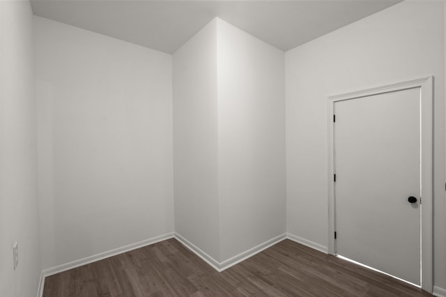 spare room with dark wood-type flooring and baseboards