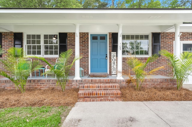property entrance with brick siding and covered porch
