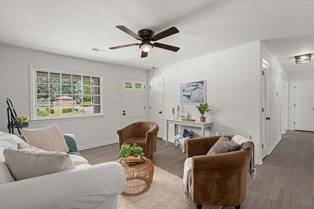 living area featuring wood finished floors, baseboards, and ceiling fan
