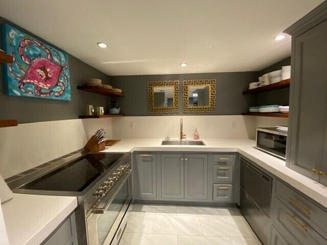 kitchen featuring high end range, open shelves, a sink, and dishwasher