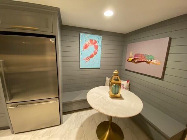 interior space featuring wood walls, stainless steel fridge, and recessed lighting