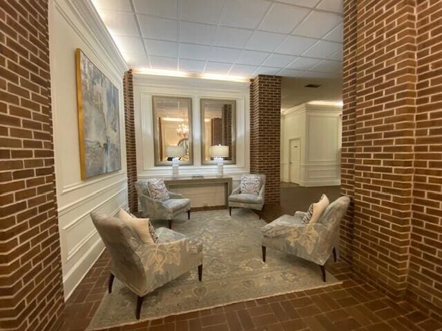 sitting room with a decorative wall, brick floor, and brick wall