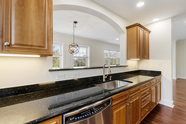 kitchen featuring dark stone countertops, stainless steel dishwasher, dark wood-type flooring, and a sink