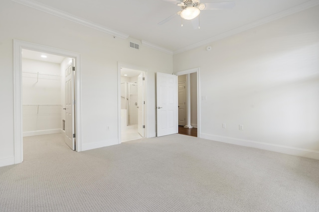 unfurnished bedroom with a walk in closet, baseboards, ornamental molding, and carpet flooring