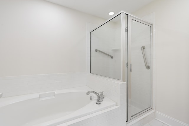 bathroom featuring a shower stall, a garden tub, and baseboards