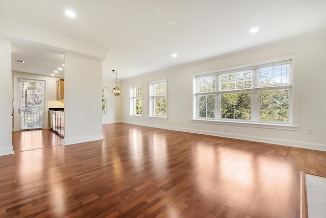 unfurnished living room featuring crown molding, dark wood-style floors, baseboards, and a chandelier