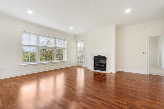 unfurnished living room featuring wood finished floors, a healthy amount of sunlight, a fireplace, and ornamental molding