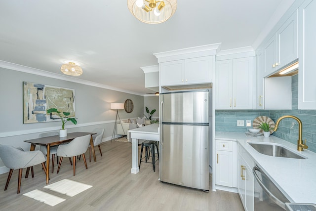 kitchen with sink, light hardwood / wood-style flooring, backsplash, white cabinets, and appliances with stainless steel finishes