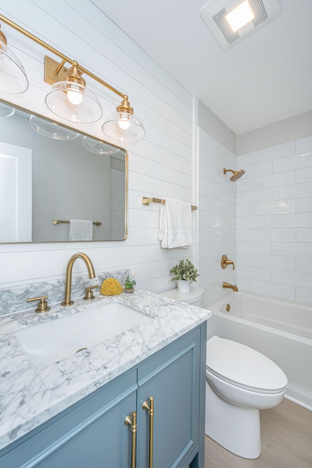 full bathroom featuring vanity, toilet, tiled shower / bath, and wood walls