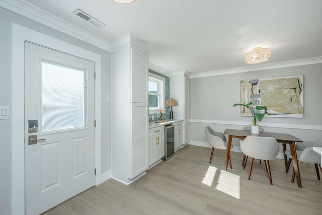 kitchen with white cabinetry, crown molding, a wealth of natural light, and light hardwood / wood-style flooring