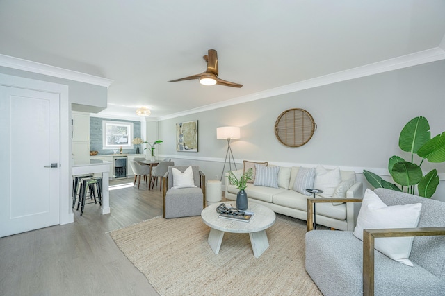 living room featuring ceiling fan, light hardwood / wood-style floors, ornamental molding, and wine cooler