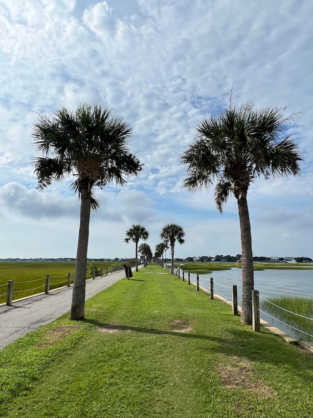 view of property's community featuring a rural view, a yard, and a water view