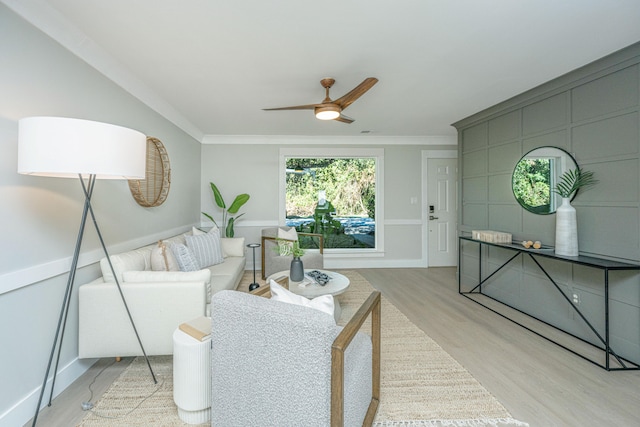 living room featuring ceiling fan, light wood-type flooring, and crown molding