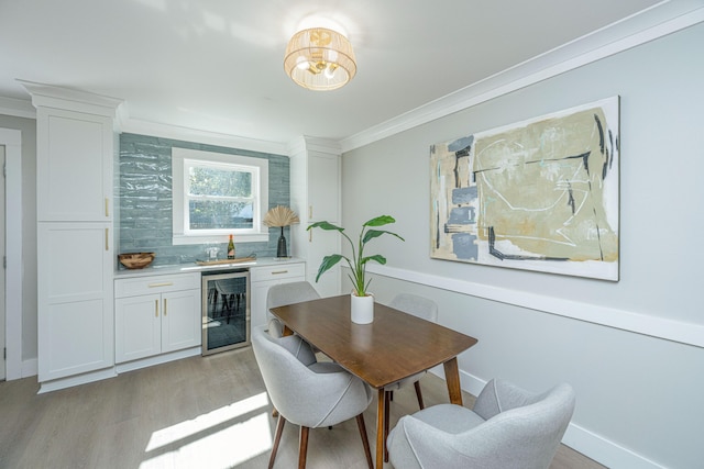 dining space featuring indoor bar, light hardwood / wood-style flooring, wine cooler, and ornamental molding