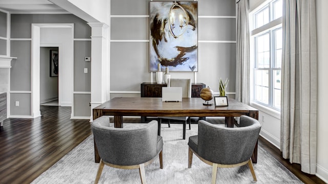 dining space featuring dark wood-type flooring, crown molding, ornate columns, and a healthy amount of sunlight