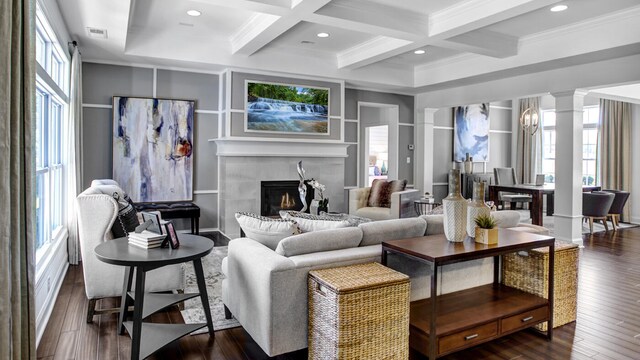 living room with dark hardwood / wood-style floors, a wealth of natural light, a tiled fireplace, and ornate columns