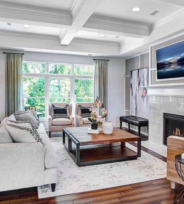 living room featuring coffered ceiling, a tile fireplace, hardwood / wood-style floors, and crown molding