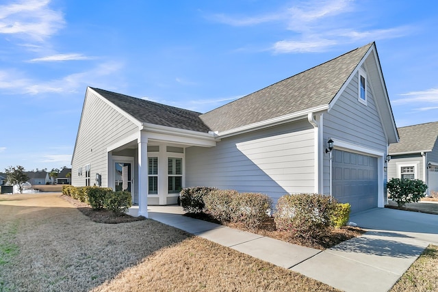 view of home's exterior featuring a garage, concrete driveway, and roof with shingles