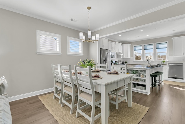 dining space featuring dark hardwood / wood-style flooring, plenty of natural light, ornamental molding, and a chandelier