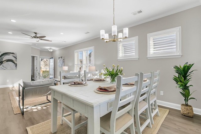 dining area with crown molding, ceiling fan with notable chandelier, and light hardwood / wood-style floors