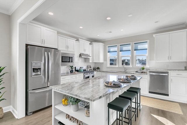 kitchen featuring stainless steel appliances, white cabinetry, a center island, and light stone counters