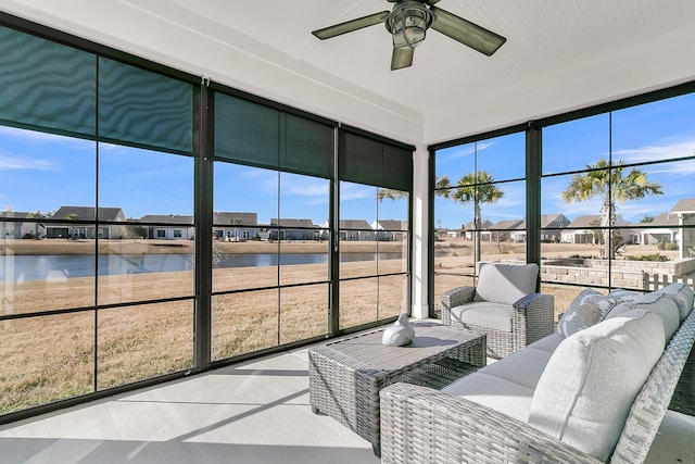 sunroom featuring ceiling fan and a water view