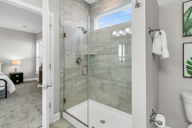 bathroom with ornamental molding, toilet, and an enclosed shower