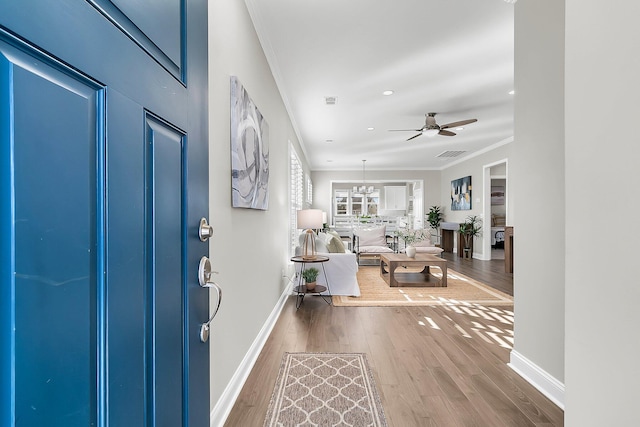 entrance foyer featuring wood-type flooring, ornamental molding, and ceiling fan with notable chandelier