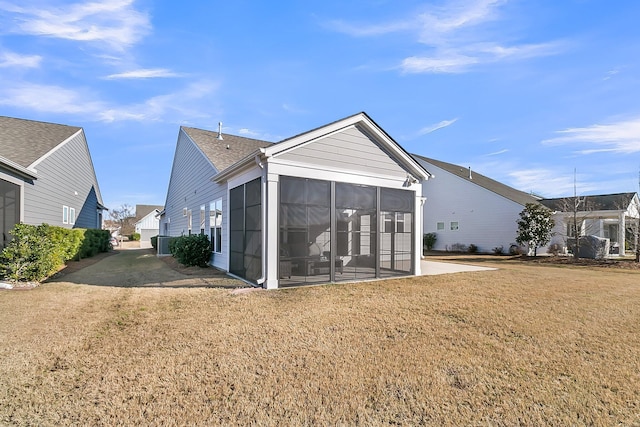 back of property with a lawn and a sunroom