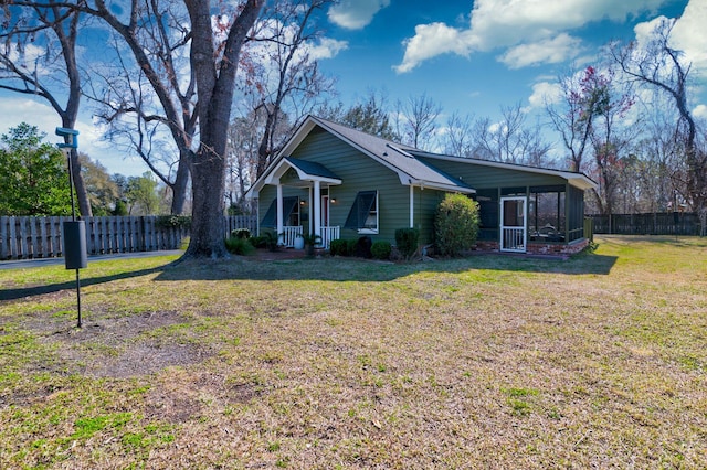 view of front facade featuring a front lawn, fence, covered porch, and a sunroom