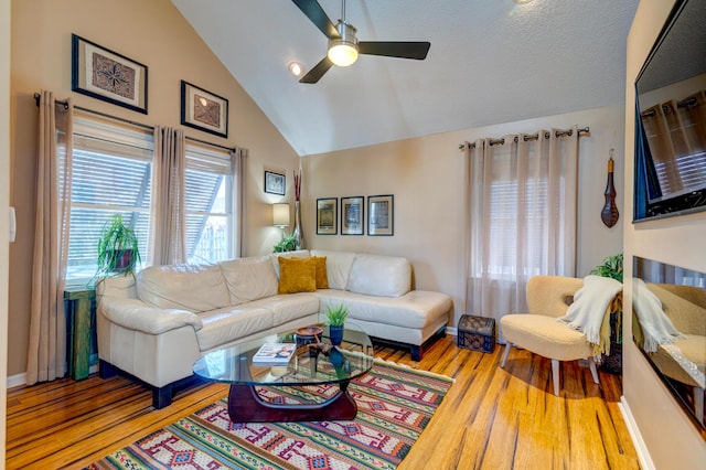 living room featuring lofted ceiling, wood finished floors, baseboards, and ceiling fan